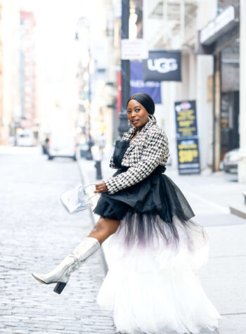 A woman wearing a tulle dress and silver boots on a city street
